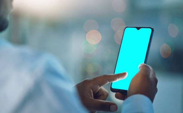 istock Closeup hands of african man using a phone while standing in his office. African american business man sending a text message while working late at night at his work. Putting in overtime after hours 1399178566