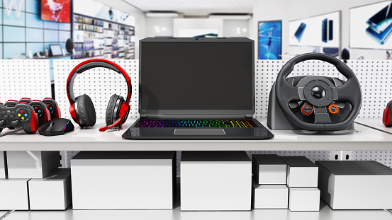 Laptop computers, gaming accessories and peripherals standing on the shelves of a technology store.