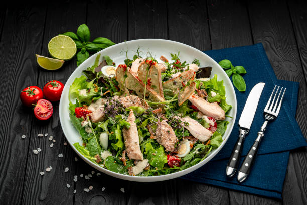 istock Fresh caesar salad in white plate on dark wooden table. 1399179449