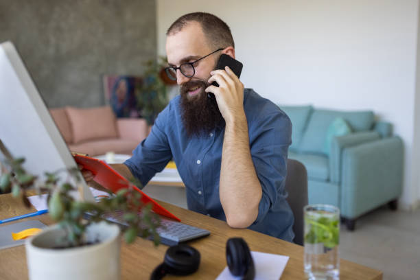 istock Caucasian man working from home office while talking on mobile phone 1399180157
