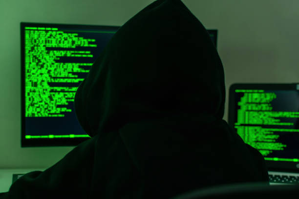 vue arrière d’un pirate informatique dans un capot noir écrivant un code de piratage de sécurité dans une pièce sombre. le concept de protection de l’information, de cybersécurité, de cybercriminalité. - cracking the code photos et images de collection