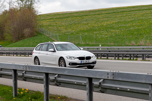 Kempten, Allgäu, Schwaben, Bavaria, Germany, may 1st 2022, a white German BMW 6th generation 3-series station wagon ('touring') approaching on the German A7 Autobahn at Kempten - with a length of 963 km between the borders of Denmark in the north and Austria in the south, the Autobahn 7 is the longest Autobahn in Germany - the majority of the German Autobahn does not have a mandatory but only an advisory speed limit