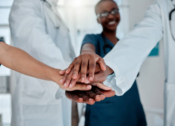 istock Group of diverse doctors stacking their hands together in support while working at a hospital. Medical professionals joining their hands in unity and motivation while working at a clinic 1399182976