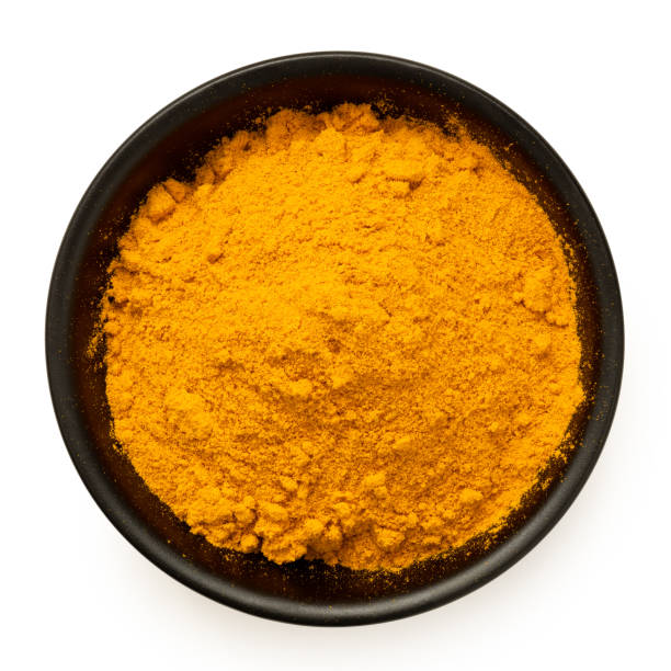 Ground turmeric in black ceramic bowl from above.