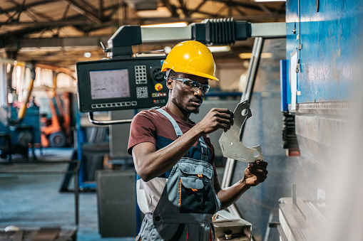 An African walks through a factory and controls the work of machines and employees