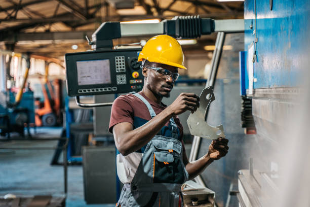 Worker in uniform operating in manual lathe in metal big workshop stock photo