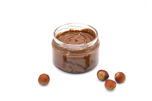 Jar of chocolate hazelnut spread, bunch of hazelnuts on white. Hazelnut butter, natural, organic product.