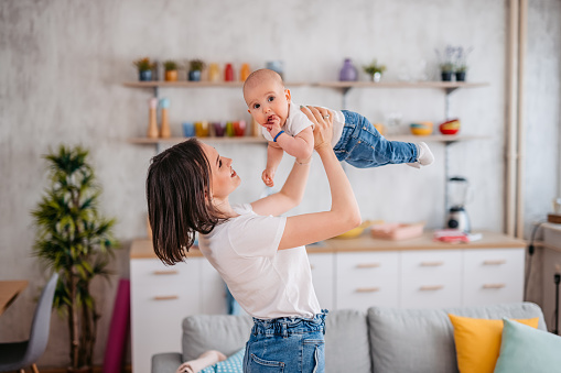 Young mother holding her baby boy in apartment.