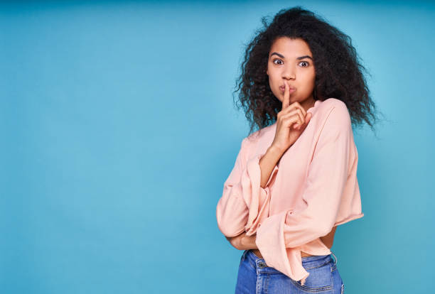 istock A young beautiful black woman holds her finger on her lips, asks for silence. 1399189796
