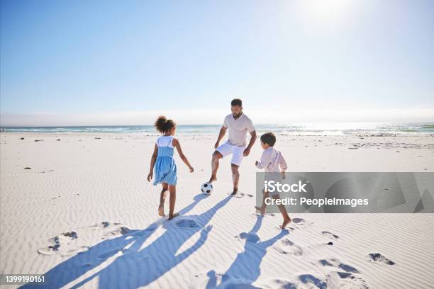 Carefree Father And Two Children Playing Soccer On The Beach Single Dad Having Fun And Kicking Ball With His Little Daughter And Son While On Vacation By The Sea Stock Photo - Download Image Now