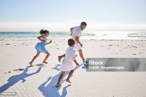 Healthy Father And Two Children Playing Soccer On The Beach Single Dad Having Fun And Kicking Ball With His Daughter And Son While On Vacation By The Sea Stock Photo - Download Image Now