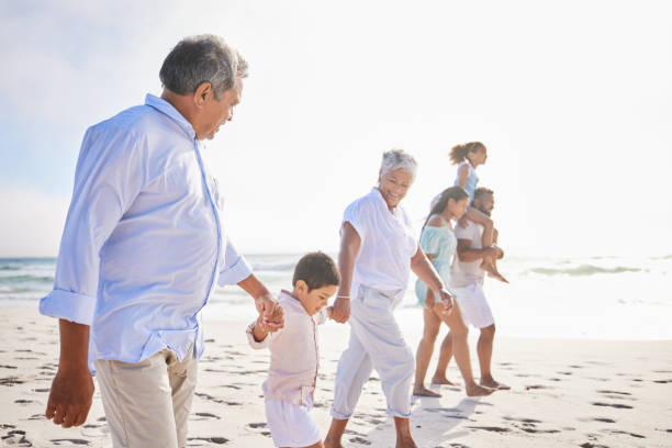 istock Three generation family on vacation holding hands while walking along the beach together. Mixed race family with two children, two parents and grandparents spending time together by the sea 1399190179