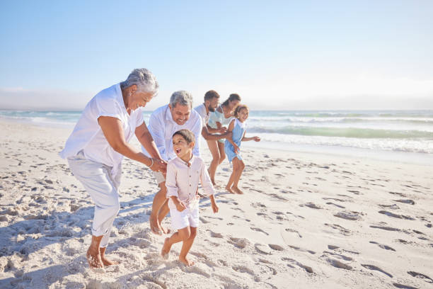 nonni che giocano con adorabile nipote sulla spiaggia. famiglia della generazione muti che si gode le vacanze al mare - chasing women men couple foto e immagini stock