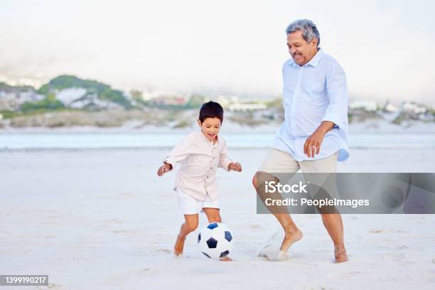 Active Grandfather And Grandson Playing Soccer On Sandy Beach Cute Little Boy Kicking Ball With His Grandpa Stock Photo - Download Image Now