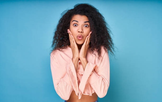 istock Surprised joyful young curly African on a blue background. 1399190416