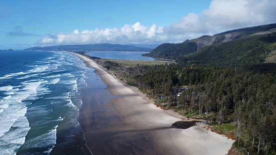 Aerial view of the Central Oregon Coast looking north from Cape Lookout toward Netarts Bay with view of beach and crashing surf.