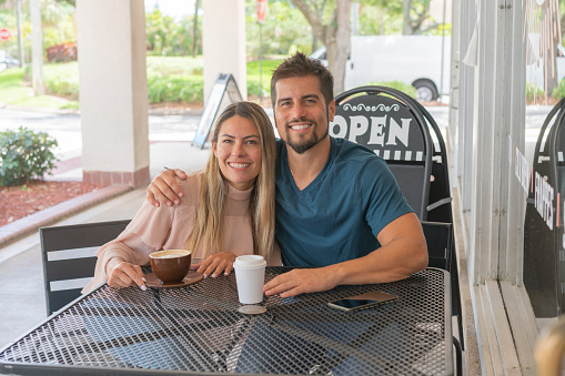 Happy couple hanging out a at outdoor table coffee shop