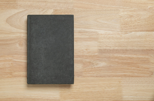 dark old book cover on wooden table for mockup blank template