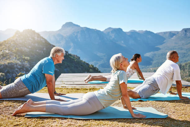 istock Group of diverse seniors practicing cobra pose during group yoga training. Mature people exercising together in nature with mountain view in background. Retirees living healthy active lifestyle 1399195127