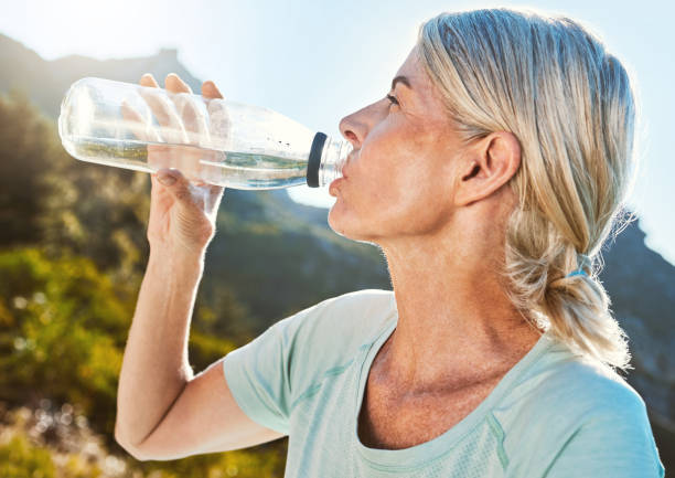 istock Active senior woman out for a run or jog in nature and drinking water while taking a break. Living active and healthy lifestyle 1399195174
