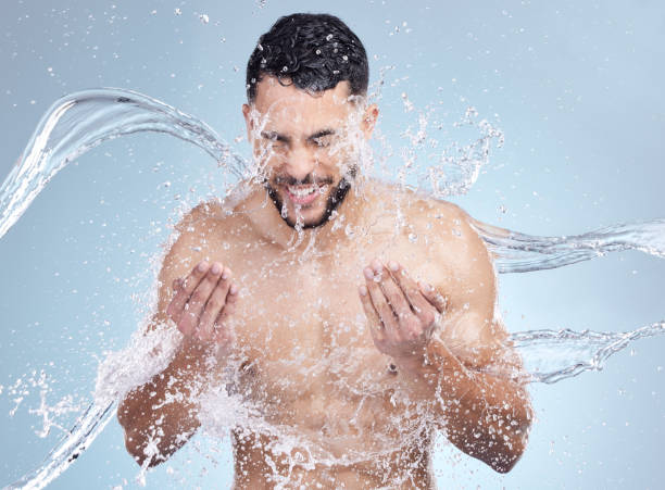 istock Studio closeup of a handsome young man splashing water on his face against a grey studio background. Hispanic male enjoying and smiling during a shower 1399196344