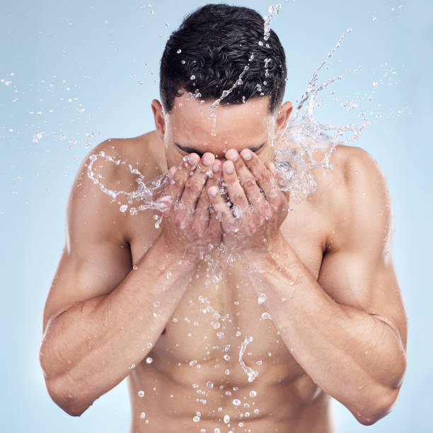 istock Studio closeup of a handsome young man splashing water on his face against a grey studio background. Hispanic male enjoying and smiling during a shower 1399196345