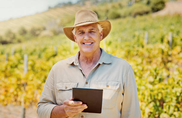 istock Smiling senior caucasian confident farmer using a digital tablet on his vineyard. Elderly man standing alone and using technology on a wine farm in summer. Happy farmer with his crops and agriculture 1399196364