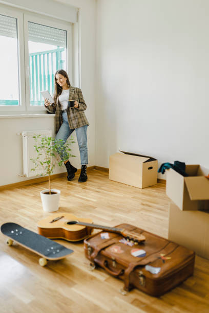 istock Smiling woman drinking coffee and using digital tablet in her new apartment 1399196630