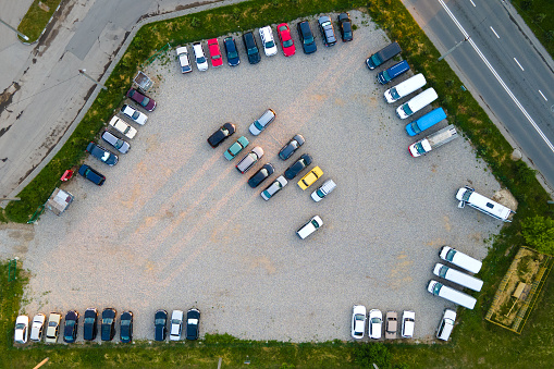 Aerial view of many colorful cars parked on parking lot in evening.