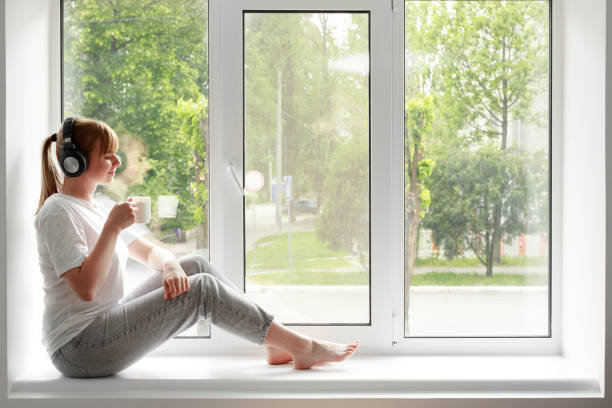 la femme à la fenêtre écoute de la musique et boit du thé. méditation à la maison - the thinker audio photos et images de collection