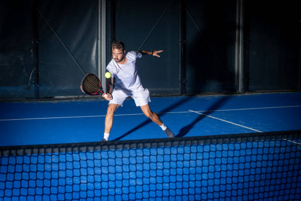 Sporty european man in white t-shirt playing padel tennis indoor