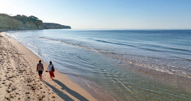 istock Aerial view of mature couple walking down sandy beach 1399201680