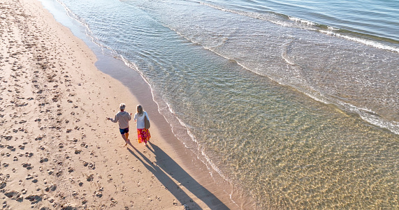 They chat as they walk barefoot, along the Atlantic Ocean, on a summer morning