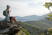 istock Female hiker relaxes at viewpoint, at sunrise 1399202056