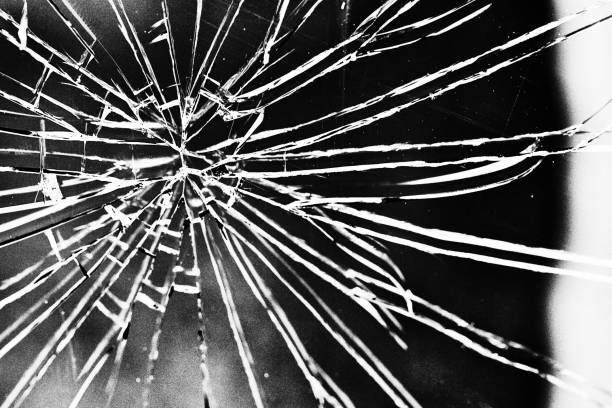 istock Dramatic radiating cracks in broken window in grainy black-and-white 1399202126
