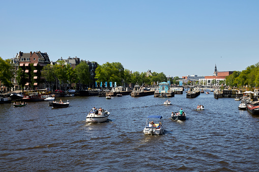 Maarssen, the Netherlands - July 15, 2009: The village center of Maarssen in summer, with the river Vecht flowing through. Maarssen is situated just outside the city of Utrecht, to the north. A recreational boat is passing by.