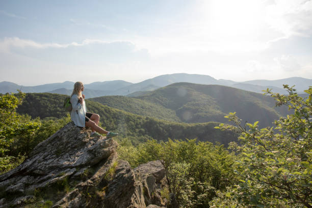 istock Female hiker relaxes at viewpoint, at sunrise 1399202271
