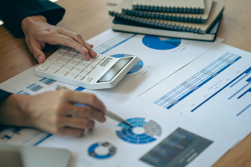 Close-up of businessman holding pen pointing to graph graph in document Corporate financial marketing, research, development, planning, management, strategy, analysis, business office concept.