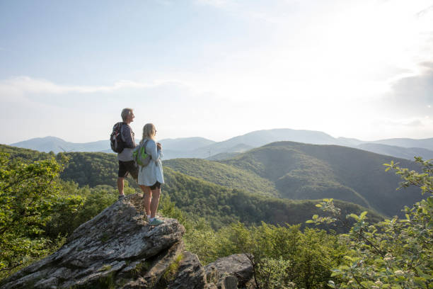 mature hiking couple relax at viewpoint - beautiful tree day rock imagens e fotografias de stock