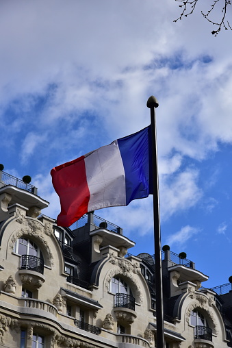 French flag fluttering against blue sky in the streets of Paris