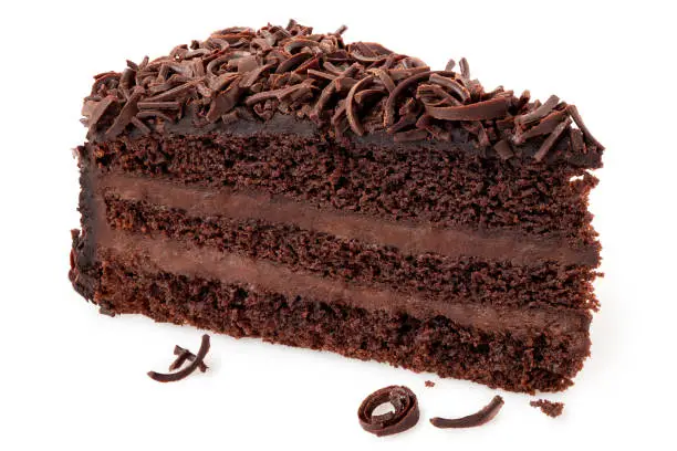 Slice of chocolate cake with cream filling and chocolate shavings isolated on white.