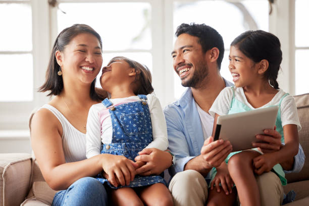 istock Young happy family spending quality time together on a sofa and using a digital tablet to watch their favourite shows at home 1399203616