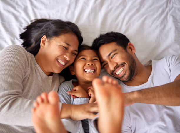 istock Family of three laughing and having fun while lying in a bed together 1399204489