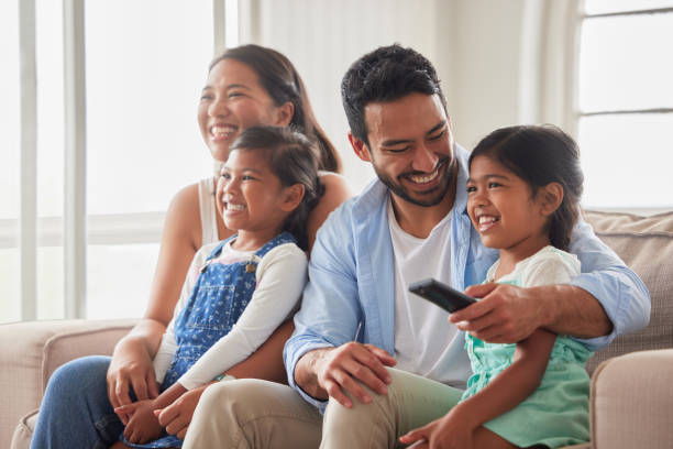 istock Young family looking safe and content while watching tv peacefully together on a sofa at home 1399205120