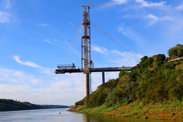 istock Bridge in construction over the river. Blue sky with clouds and sunset light in the horizon. Bridge over Iguaçu river in the border Brazil and Paraguai to connect both countries. Architecture and construction. Engineering work with modern technology. 1399205835