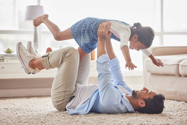istock Handsome young single father playing with his daughter and looking happy while laughing on the lounge floor at home 1399207565