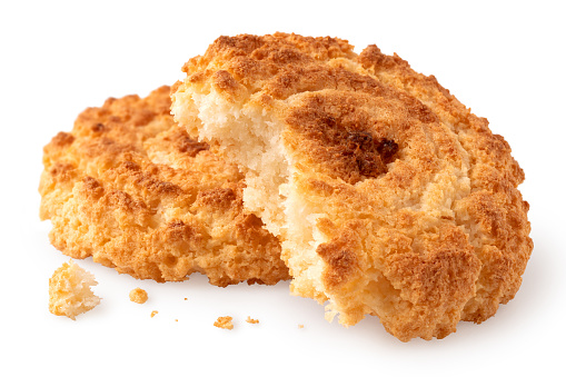 Two coconut cookies isolated on white. One partially eaten with crumbs.