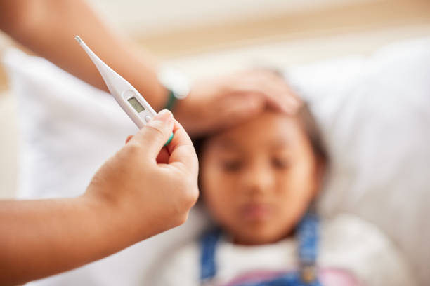 istock Sick little girl looking weak while resting on the sofa and having her temperate taken at home by her mother 1399210390