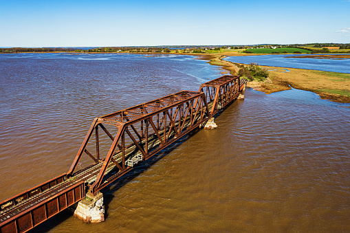 Aerial drone view of an abandoned railway bridge crossing a tidal river.