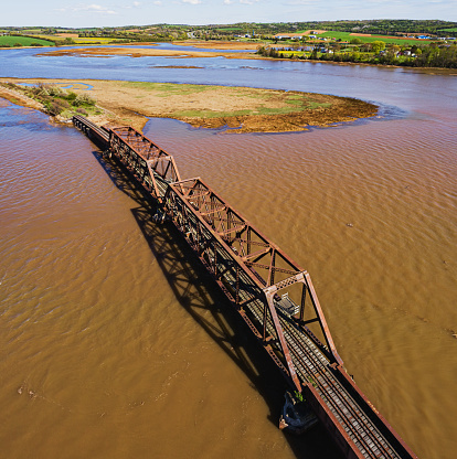 Aerial drone view of an abandoned railway bridge crossing a tidal river.